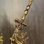 Close up detail of the top of the khatvanga staff featuring heads, skull and a trident.