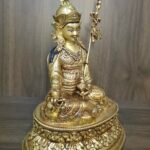 Left side angle of Guru Rinpoche statue showing staff and lotus base.