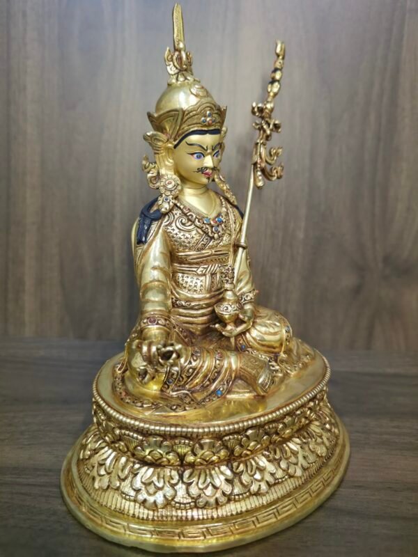 Left side angle of Guru Rinpoche statue showing staff and lotus base.