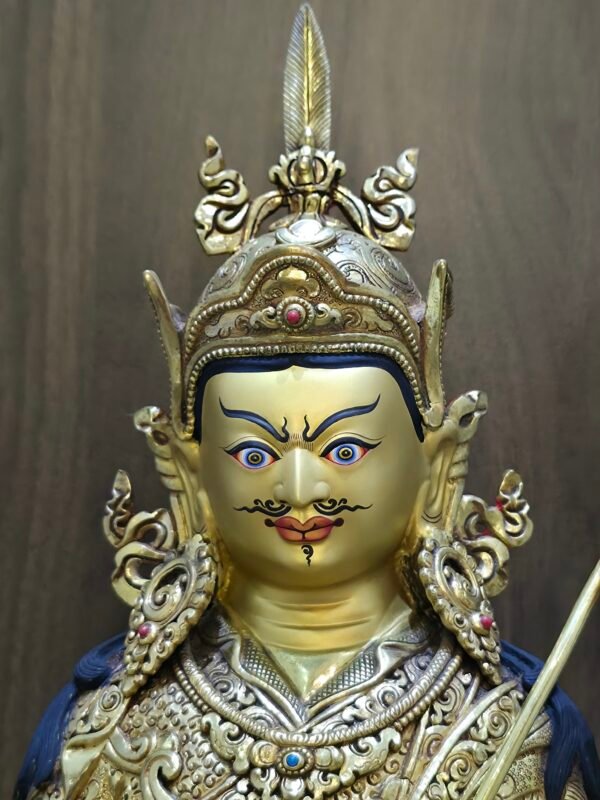 Close up of Guru Rinpoche's hand-painted face featuring a semi-wrathful expression, mustache, and lotus hat.