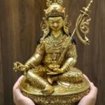 A hand holding the bottom of the statue to demonstrate the scale and the raw copper finish of the base plate.