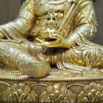 Detail macro shot of the statue's torso showing the golden skull cup held at the heart and intricate jewellery.