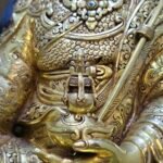Detail shot of Guru Rinpoche's left hand holding the Kapala skull cup containing the Bumpa long-life vase.