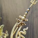 Close up detail of the top of the khatvanga staff featuring a trident and heads and a skull.