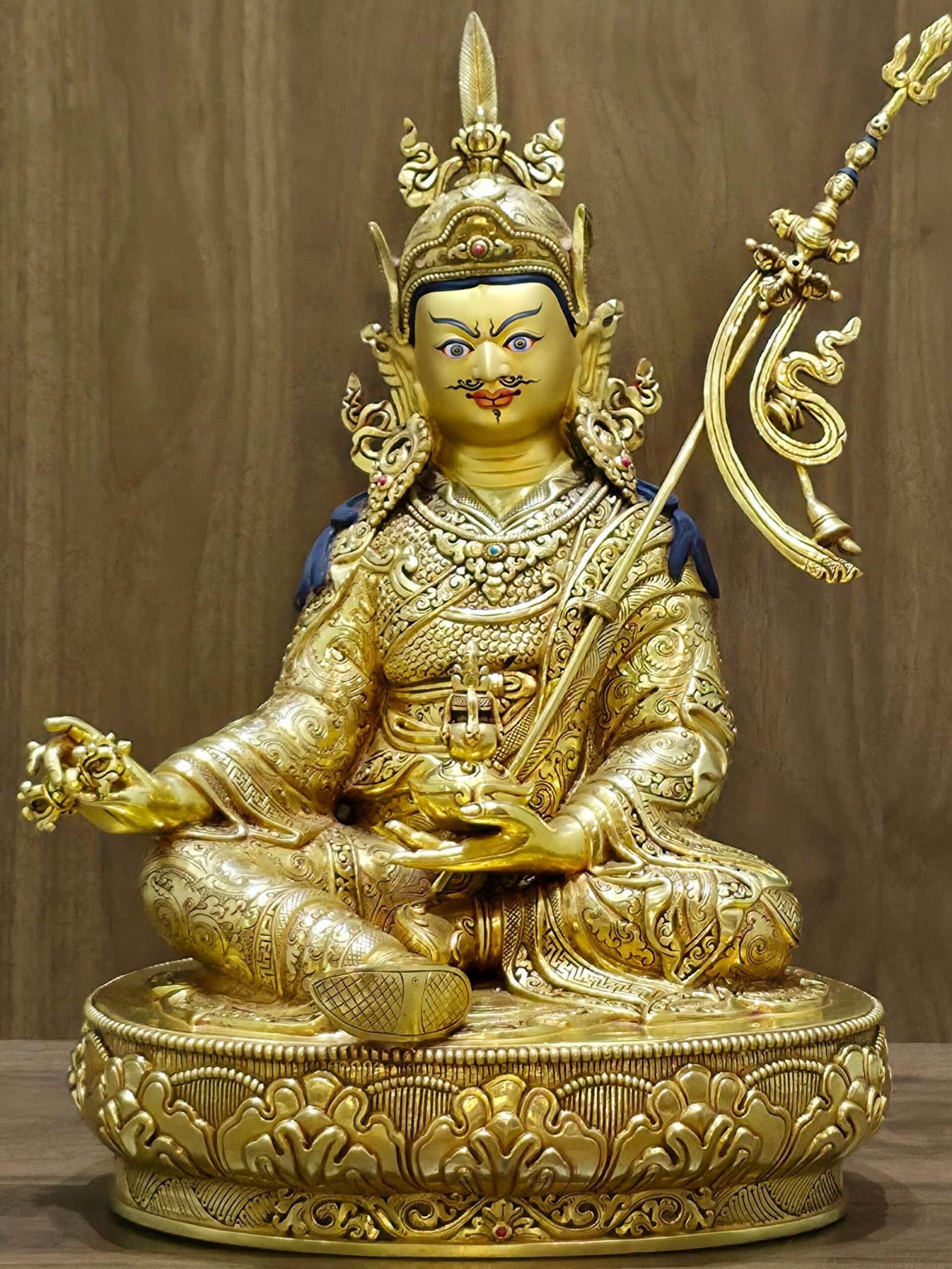 Full front view of 24K gold plated Guru Rinpoche statue seated on a lotus base with khatvanga staff.