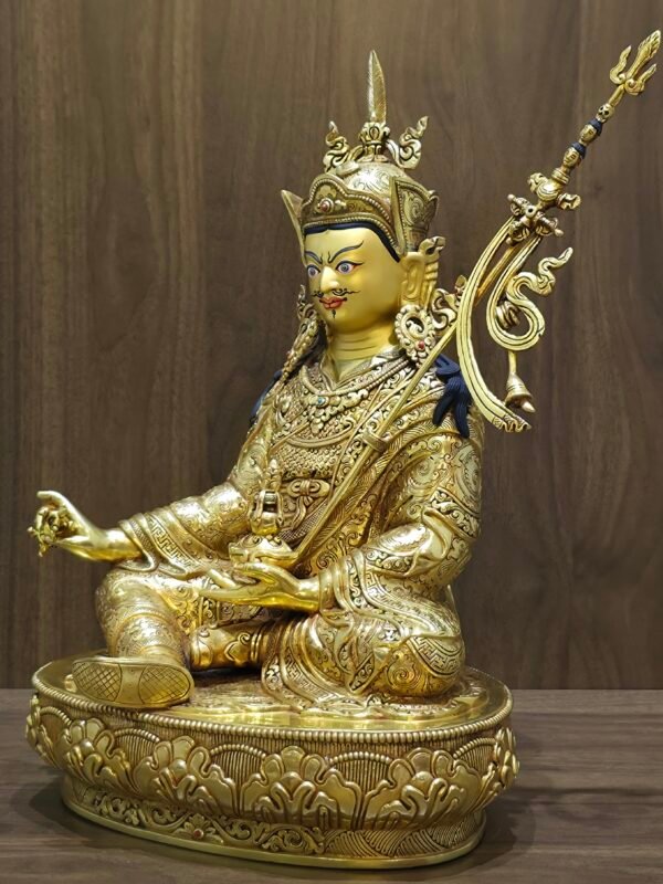 Right side angle of the Lotus Born Guru statue holding a vajra in the right hand and skull cup in the left.