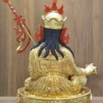 Back view of gold Guru Rinpoche statue showcasing the detailed engravings on the robes and flowing hair.