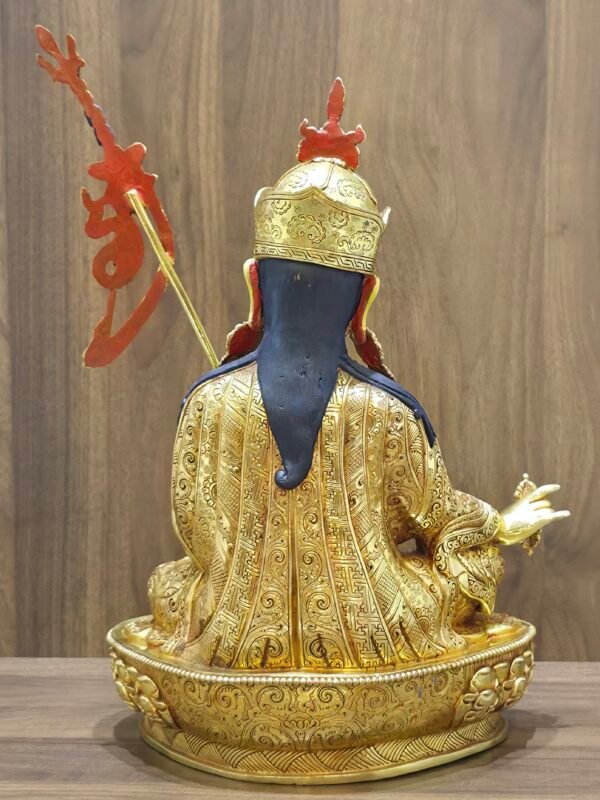 Back view of copper Padmasambhava statue showing flowing blue hair, flaming trident staff, and detailed robe carvings.