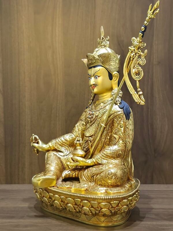 Side profile view of gold plated Guru Rinpoche statue showing the Khatvanga staff and ear ornaments.