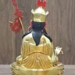 ack view of Padmasambhava statue showing detailed hand-chased floral patterns on robes and flowing hair.