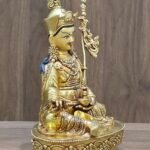 Left angle view of gold plated Padmasambhava statue showing skull cup and khatvanga staff position.