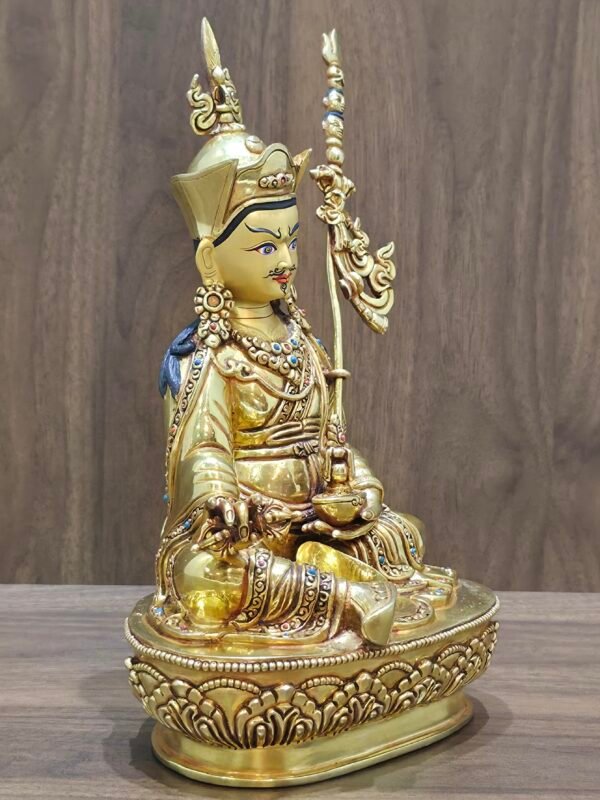 Left angle view of gold plated Padmasambhava statue showing skull cup and khatvanga staff position.