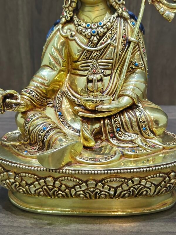 Detail of Guru Rinpoche hands holding Vajra and Long Life Vase, showing intricate gold metalwork.