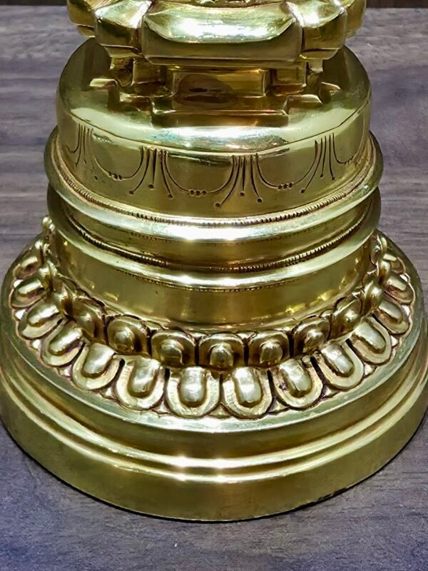 Close-up of gold-plated copper Tibetan chorten stupa base with lotus petals and engraved band.