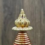 Finial detail of gold-plated copper Tibetan stupa with lotus top and red-banded spire.