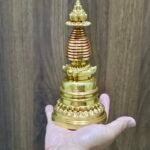 Handheld gold-plated copper Tibetan chorten stupa reliquary (20 cm) shown for scale.
