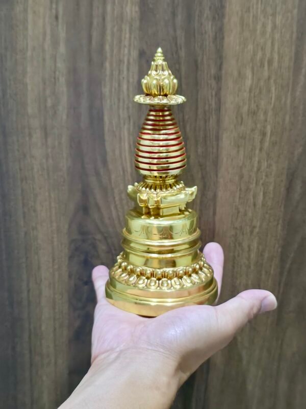 Handheld gold-plated copper Tibetan chorten stupa reliquary (20 cm) shown for scale.