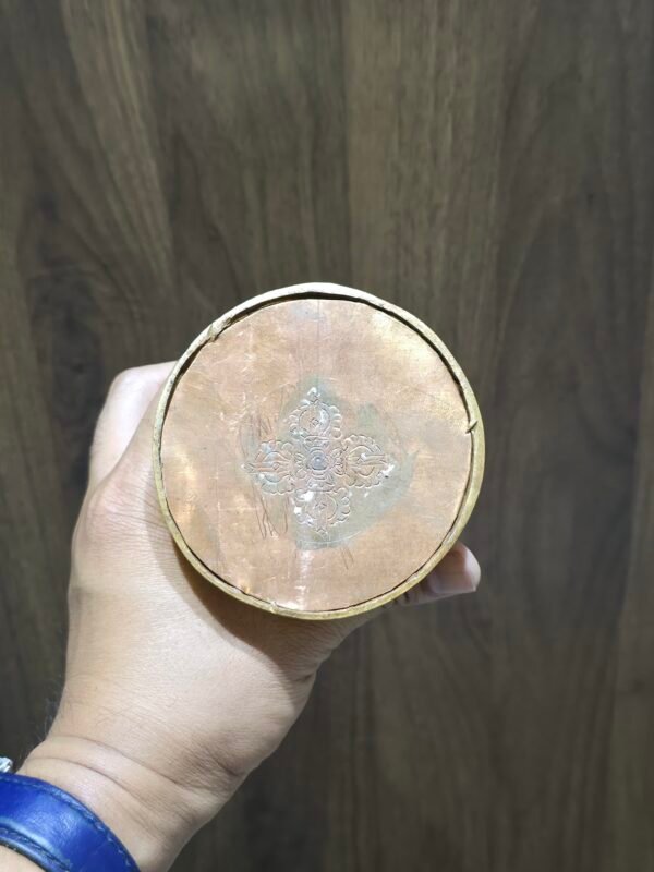 Underside of openable gold-plated copper stupa base with engraved double vajra, shown in hand.
