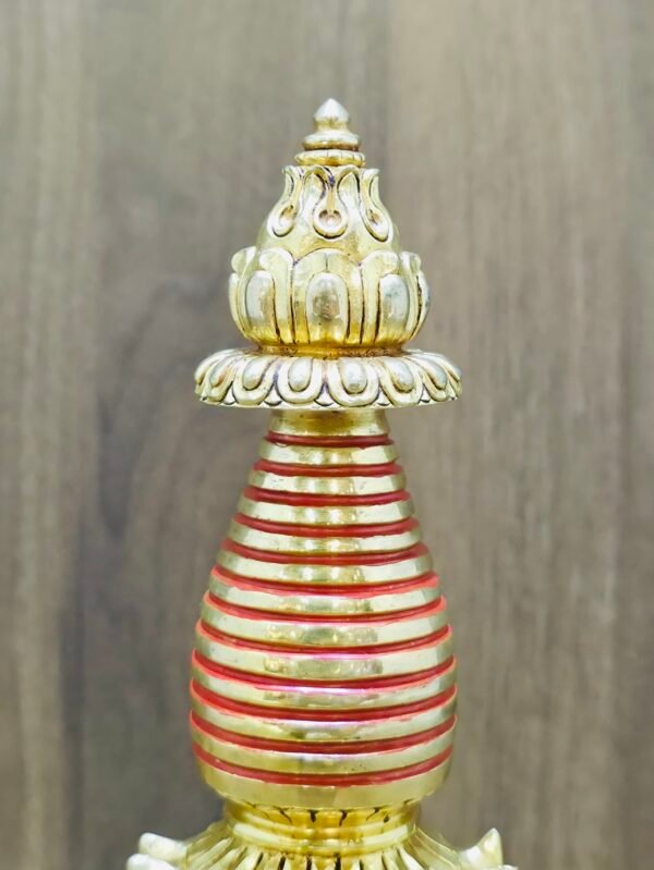 Close-up of spire rings and finial on Kadampa stupa chorten, red accents