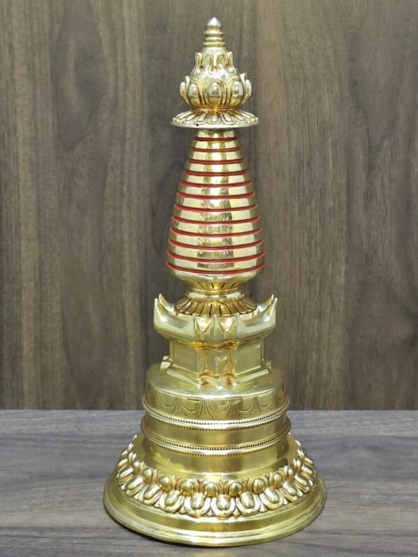 Tibetan-style Buddhist stupa (chorten) in 24K gold-plated copper, red accent rings on spire, front view.