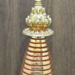 Close-up of stupa spire and finial with lotus parasol, gold-plated copper with red ring accents.