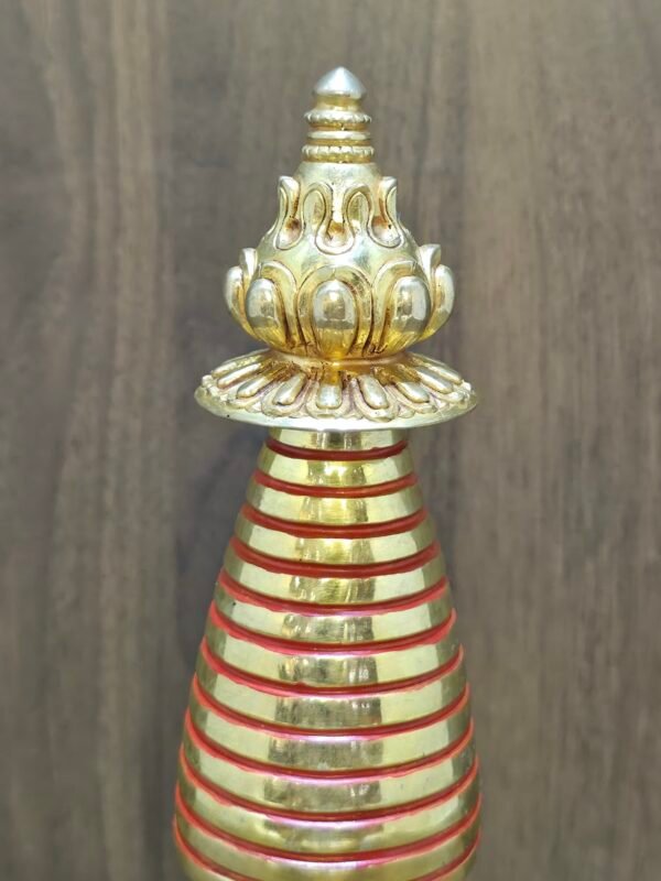 Close-up of stupa spire and finial with lotus parasol, gold-plated copper with red ring accents.