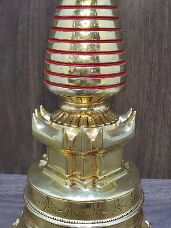 Detail of stupa pedestal and lotus base, gold-plated copper craftsmanship with red-ringed spire above.
