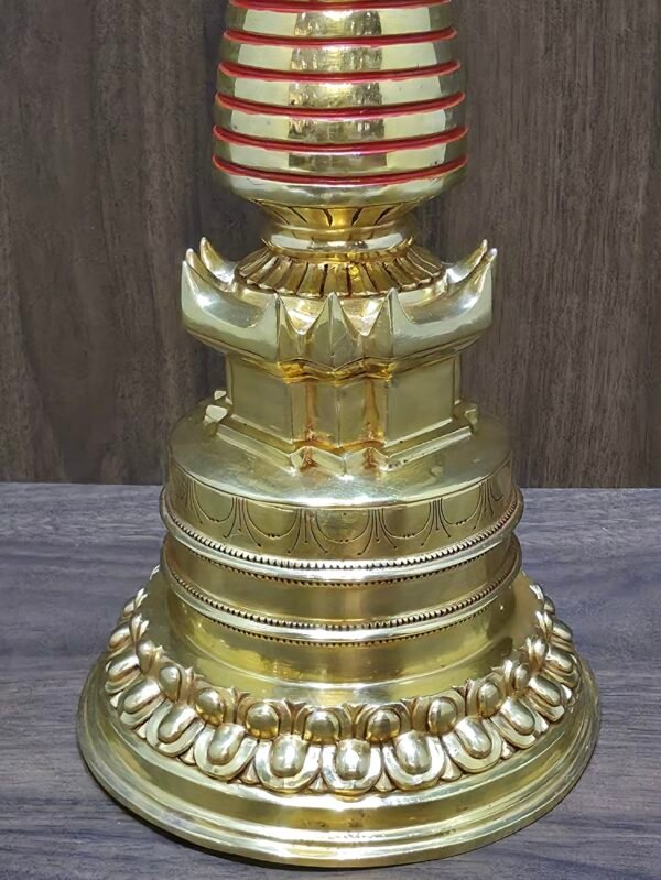 Close-up of stupa lower base with lotus petal band and carved detailing in gold-plated copper.