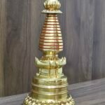 Angled side view of Tibetan Buddhist stupa (chorten), gold-plated copper with red accent rings and lotus base.