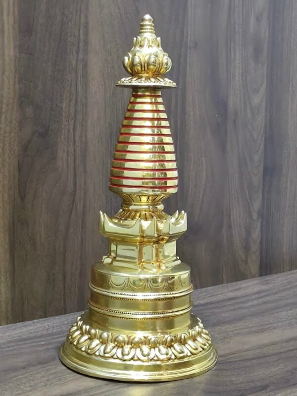 Angled side view of Tibetan Buddhist stupa (chorten), gold-plated copper with red accent rings and lotus base.