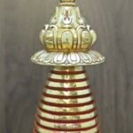 Close up of stupa finial and lotus parasol, gold plated details with red bands on the upper spire.