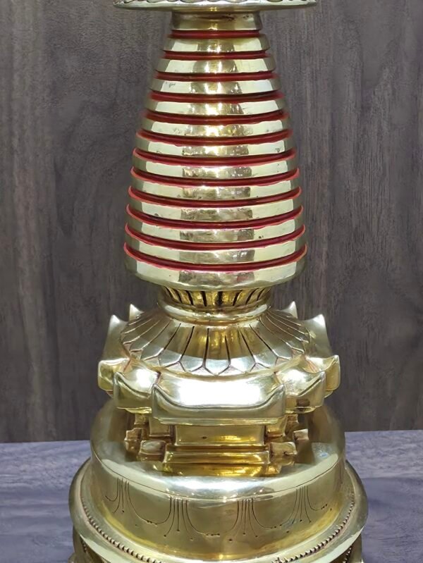 Close up of red ringed spire and lotus platform, showing polished gold plated copper surfaces.