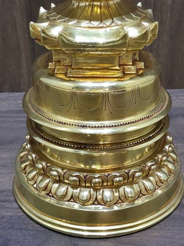 Close up of stupa base with engraved banding and lotus petal border in polished gold plated copper.