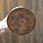 Underside of stupa showing copper base plate with engraved double vajra symbol, held in one hand.