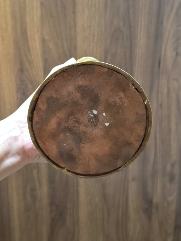 Underside of stupa showing copper base plate with engraved double vajra symbol, held in one hand.