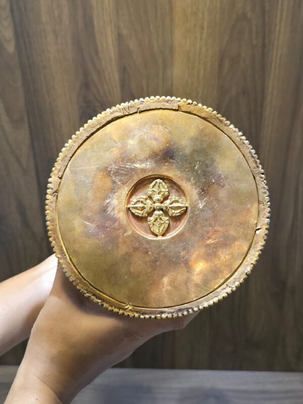 Underside of stupa base showing copper bottom plate with raised vajra emblem, held in hands.