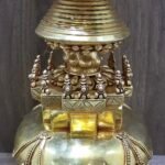 Close up of stupa mid section with square platform, small finials, and engraved lotus motifs beneath the ringed spire.