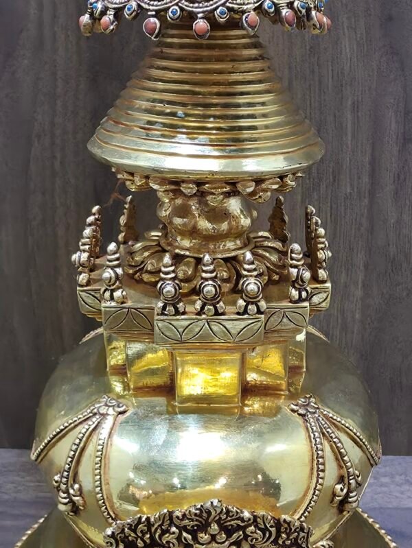 Close up of stupa mid section with square platform, small finials, and engraved lotus motifs beneath the ringed spire.