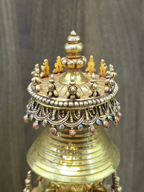 Close up of stupa canopy with bead fringe and blue and coral inlays, topped with stacked jewel finial.