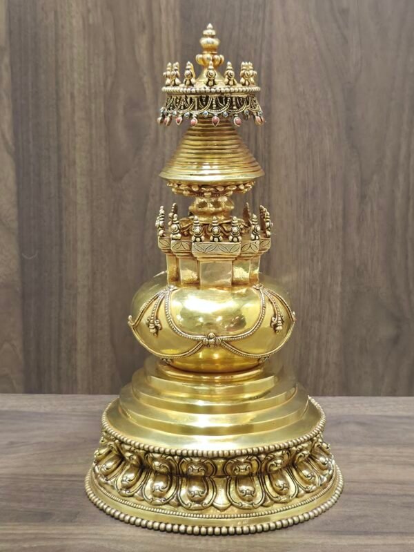 Back view of gold plated copper stupa showing smooth rounded body with applied garlands and stepped pedestal base.