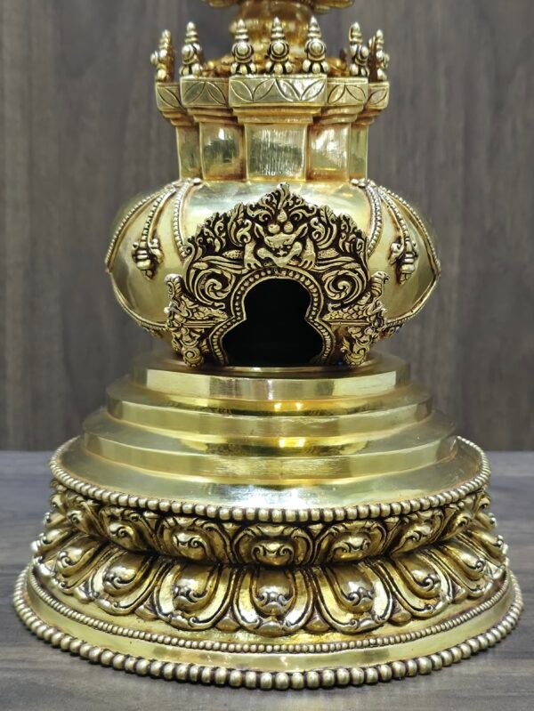 Close up of carved torana arch opening and stepped base of gold plated copper stupa, with lotus petal detailing.