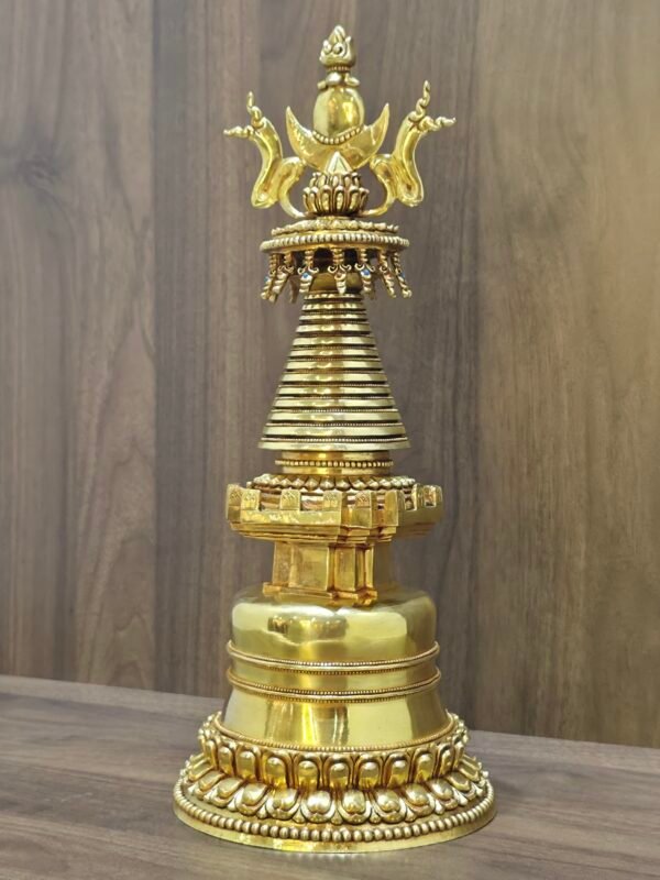 Right angled view of gold plated copper Tibetan stupa, showing stepped base and ringed spire profile.