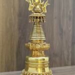 Angled view of Tibetan style stupa in gold plated copper, highlighting layered base and decorative crown.