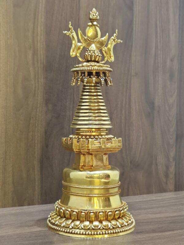 Angled view of Tibetan style stupa in gold plated copper, highlighting layered base and decorative crown.
