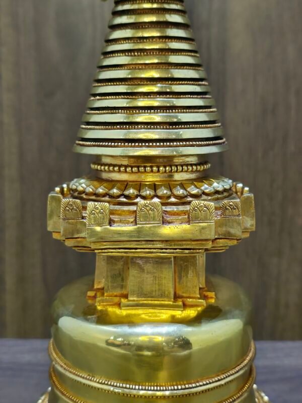 Detail of the upper midsection, striped conical spire and square platform with carved edging, gold plated finish.