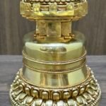 Close up of the base, polished gold plated copper with layered bands and lotus petal carving around the foot.