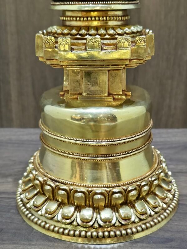 Close up of the base, polished gold plated copper with layered bands and lotus petal carving around the foot.