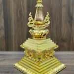 Full stupa centered on wooden backdrop with wide stepped base, red banded conical spire, and curling side ornaments.