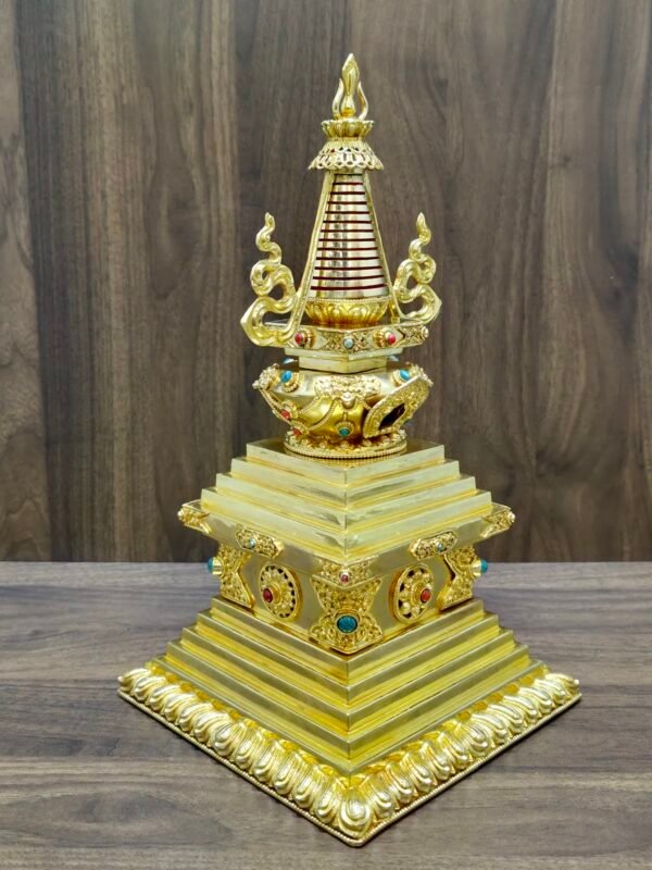 Full stupa centered on wooden backdrop with wide stepped base, red banded conical spire, and curling side ornaments.