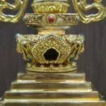 Three quarter view highlighting stepped base corners, lotus rim, and decorative panels with red and turquoise colored inlays.